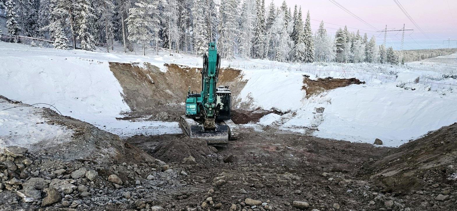 Kaivinkone kaivamassa lumisella työmaalla